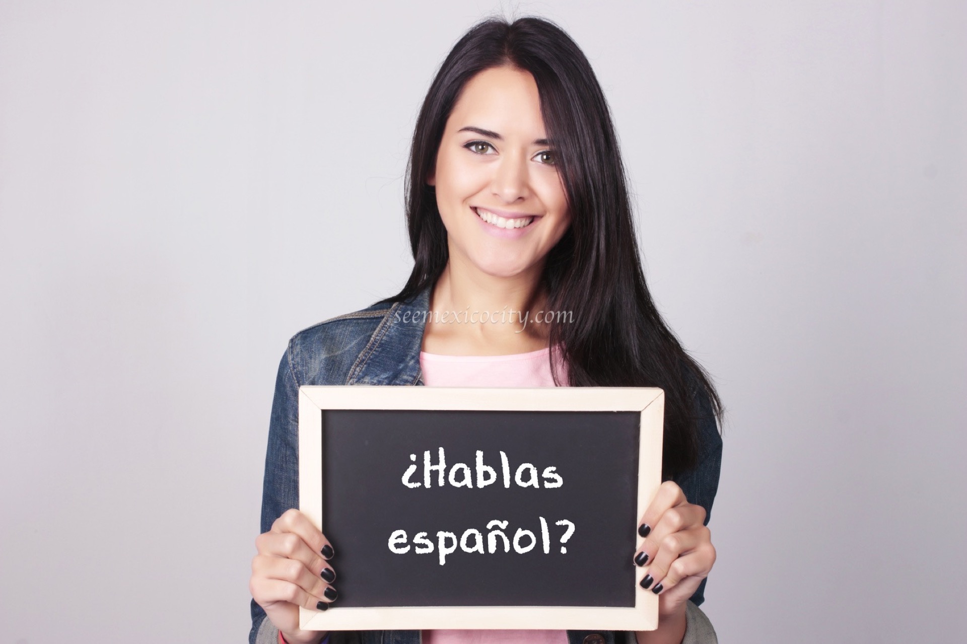 Young woman holding sign "Hablas español?""